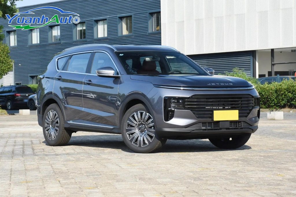 A grey Jetour X70 Plus SUV parked outside a factory building